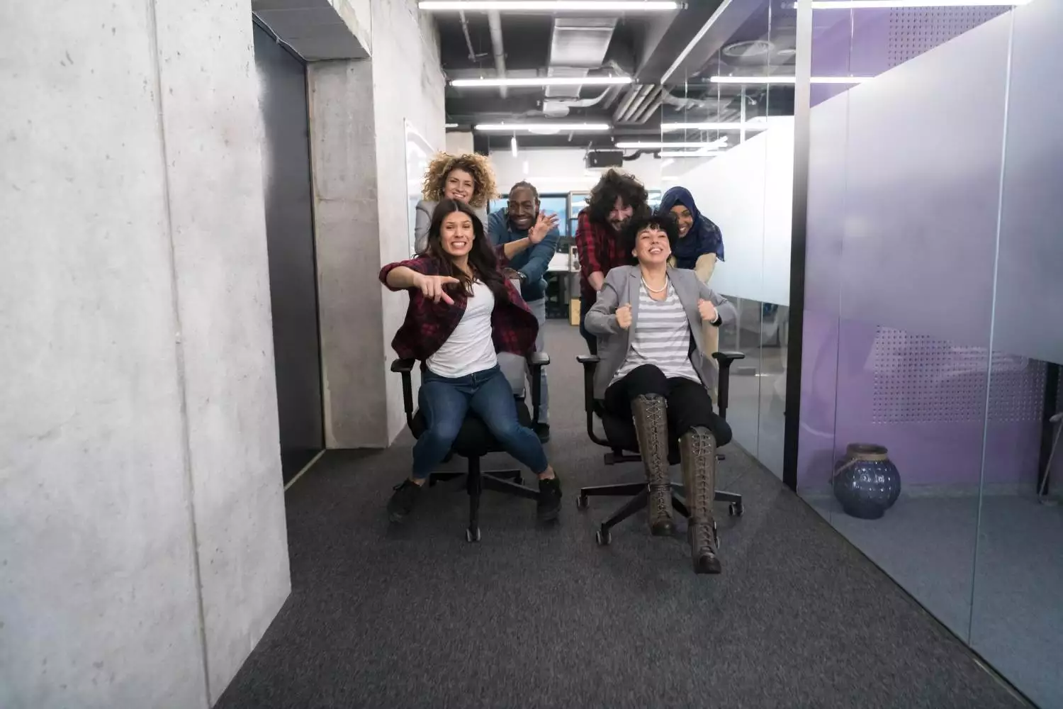 multiethnics startup business team of software developers having fun while racing on office chairs,excited diverse employees laughing enjoying funny activity at work break